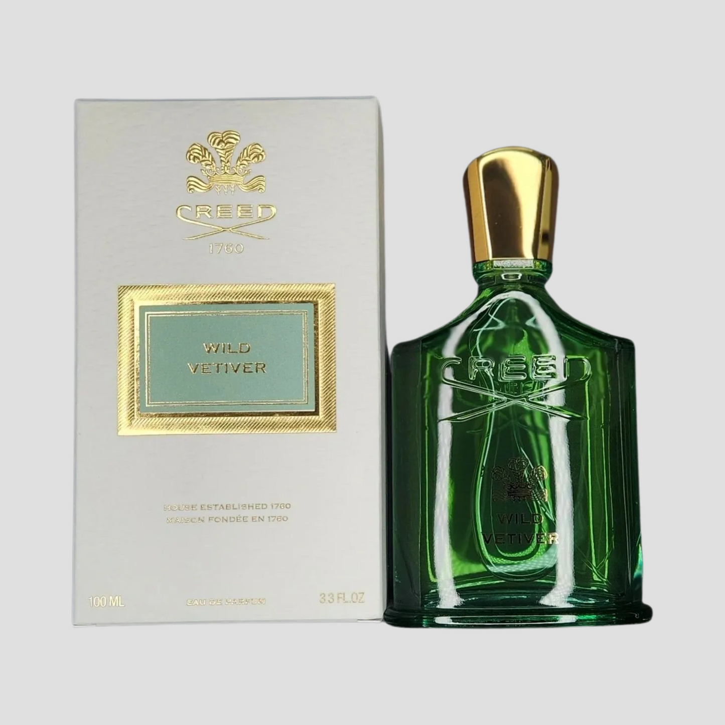 A bottle of Creed Wild Vetiver next to its box on a light grey background
